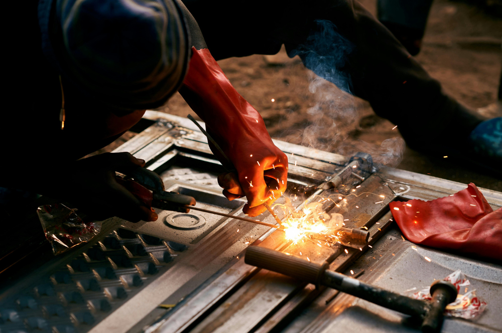 A welder focused on TIG welding, applying a torch to fuse metal components together.